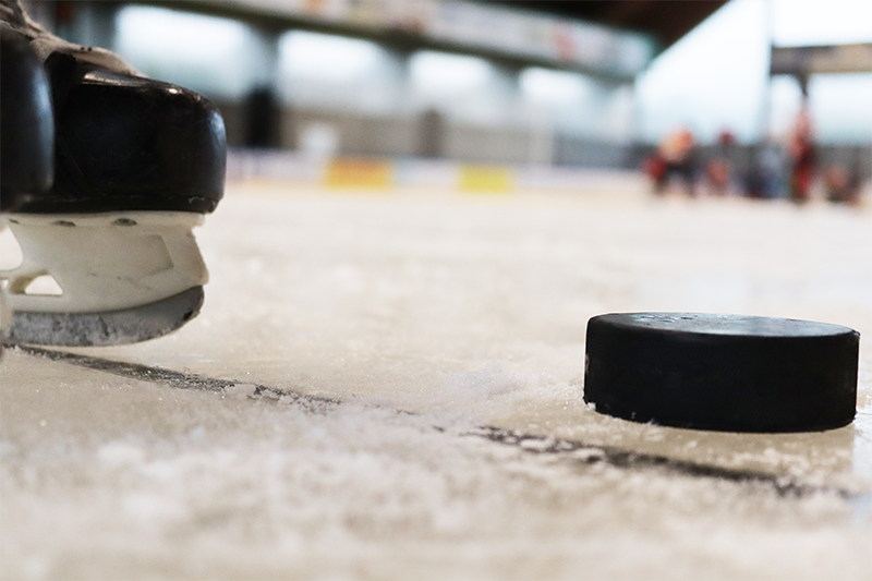 Laufschule – Schlittschuh und Puck auf dem Eis